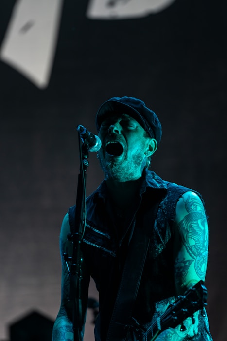 A man singing into a microphone while holding a guitar